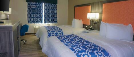 A hotel room with two beds, a desk, a chair, and a television.