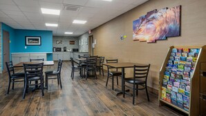 A restaurant with wooden flooring, black chairs, a counter, and a wall with a painting.