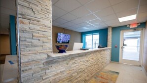 A reception area with a stone wall, a flat-screen TV, a bowl-shaped vase, and a door with an exit sign.