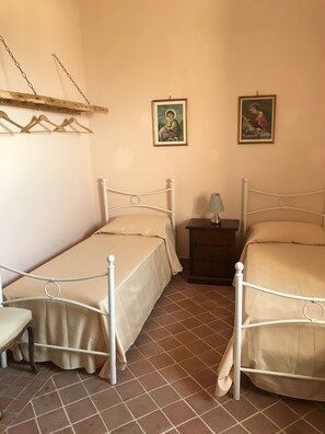 Un dormitorio con dos camas individuales, una mesita de noche, una lámpara y dos cuadros en la pared.