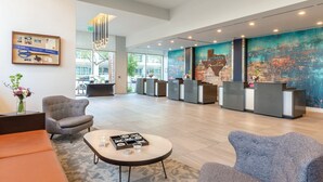 A spacious lobby with a reception desk, seating area, and a large abstract mural. - DOWNTOWN Austin with ROOFTOP Pool and BBQ Area, Fire Pit & a Fitness Center (Austin)