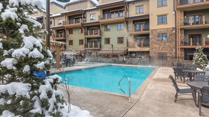 Ein mehrstöckiges Hotel mit Schwimmbad, Außenbereich und schneebedeckten Bäumen.