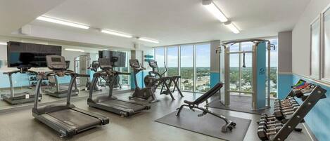 A gym with treadmills, elliptical machines, and dumbbells.
