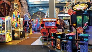 Une salle d’arcade proposant divers jeux, notamment un jeu de flipper et un jeu de course.