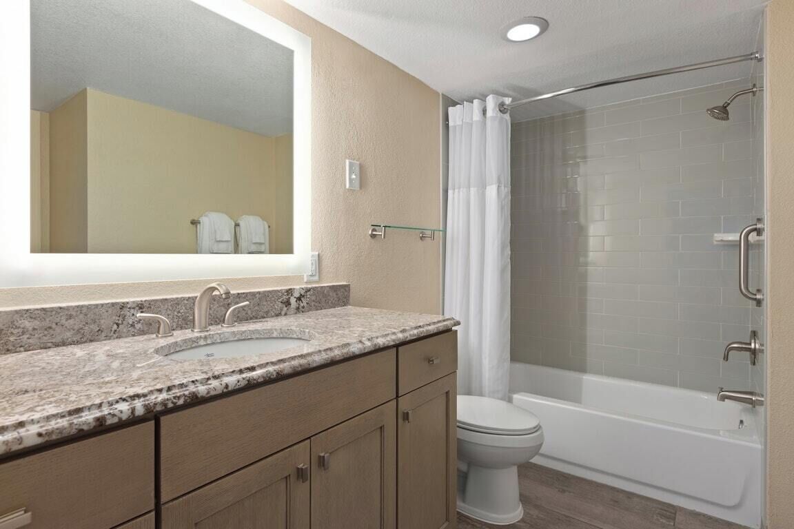 Un baño con lavamanos, espejo, inodoro y ducha.