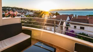 A balcony with a view of a coastal town at sunset.