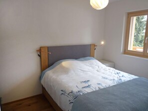 A small, neatly made bed with a grey headboard and a white and blue floral bedspread.