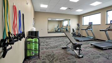 A gym with exercise equipment, a mirror, and a carpeted floor.