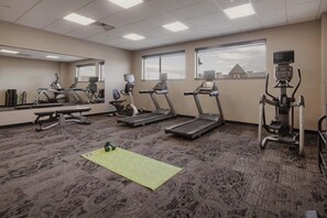 Ein Fitnessraum mit Laufbändern, einem Ergometer und einem Spiegel.