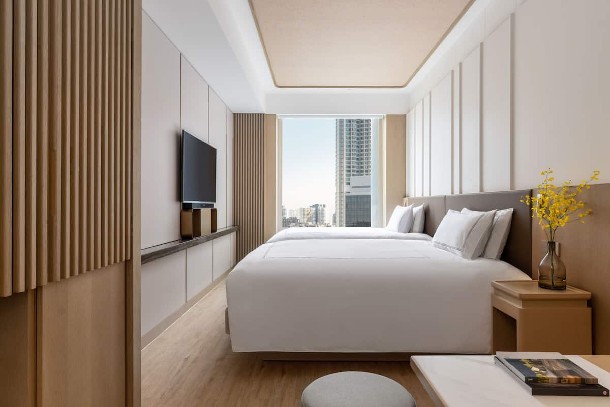 Een moderne hotelkamer met een groot bed, een flatscreen televisie, een wand van houtfineer en uitzicht op de stadshemel.