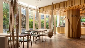 Un interior moderno con ventanas amplias, suelo de madera y una zona de estar central con mesas y sillas.