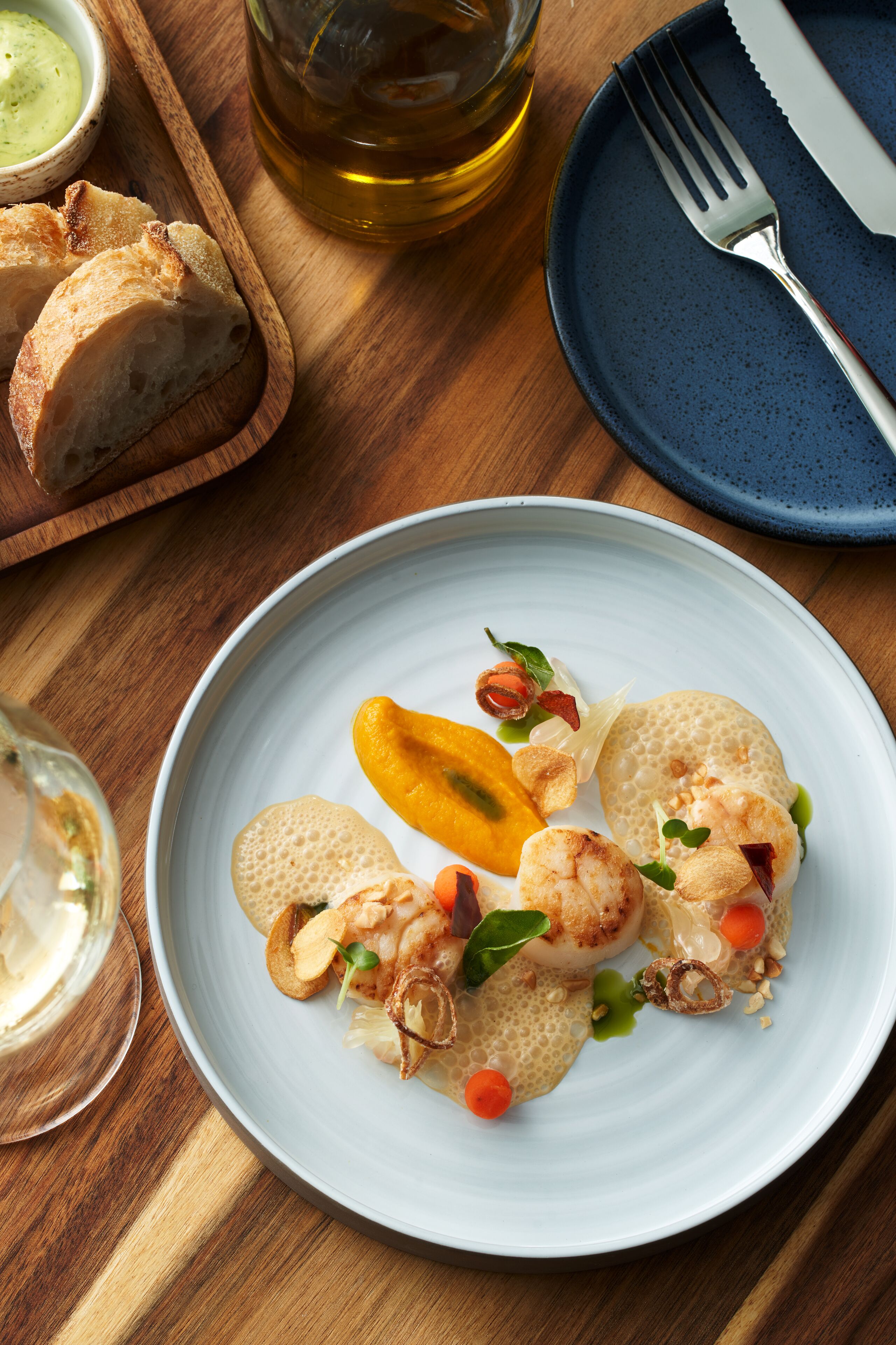 Un plato de comida con camarones, verduras y una rebanada de mango sobre un plato blanco.