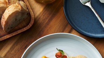 Un plato de comida con camarones, verduras y una rebanada de mango sobre un plato blanco.