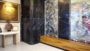 A room with a marble wall, a wooden bench, and a decorative panel. - Grand Omah Sastro (Depok)
