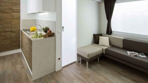A compact living space with a kitchenette, a sofa, and a window with curtains. - Mobile home with air conditioning and pool (Pietra Ligure)