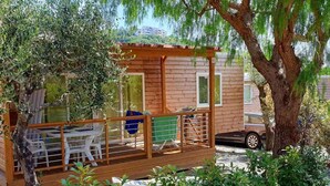 A wooden cabin with a deck, a table, and chairs. - Mobile home with air conditioning and pool (Pietra Ligure)