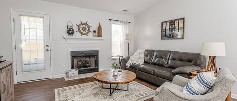 A living room with a fireplace, a sofa, a coffee table, and a lamp.