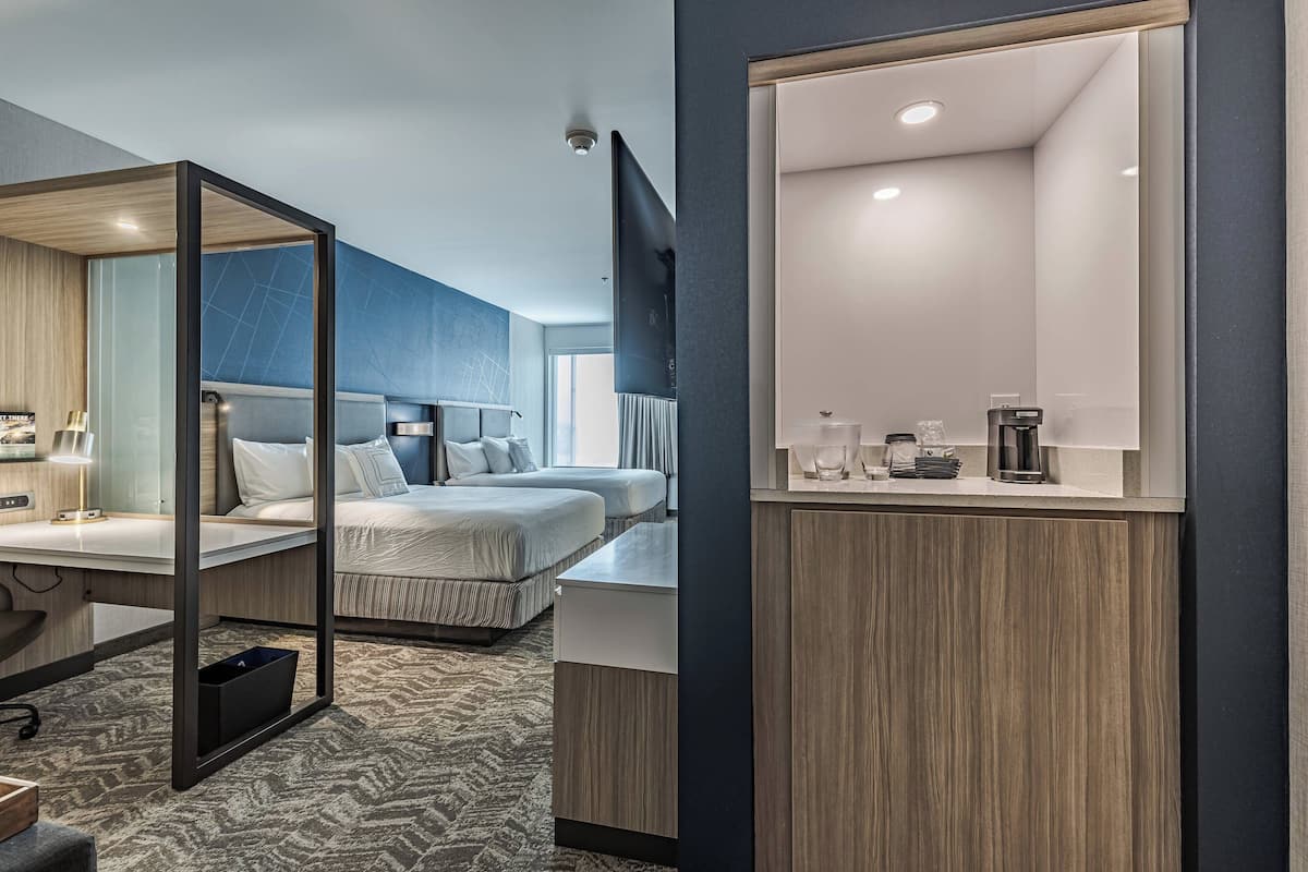 Una habitación de hotel moderna con una cama grande, un escritorio y un espejo.