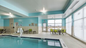 Un espace piscine intérieur équipé d’un ascenseur pour piscine, de chaises et de tables.