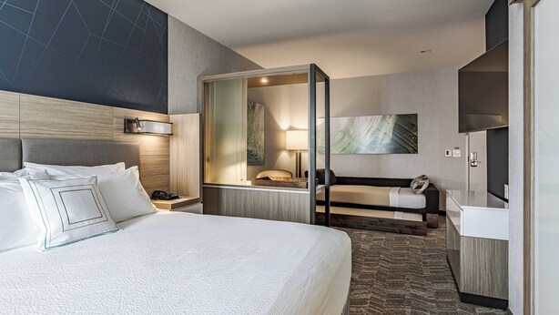 Une chambre d’hôtel moderne équipée d’un grand lit, d’un bureau, d’un canapé et d’une télévision.