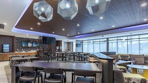 Un espace de repas moderne avec une table centrale, des chaises disposées autour, et un coin salon avec des canapés et une table basse.