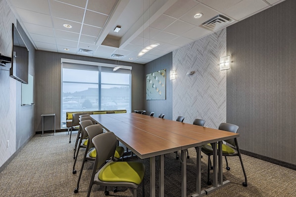 A conference room with a long table, chairs, and a large window.