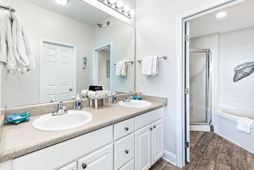 A bathroom with two sinks, a large mirror, and a shower area.