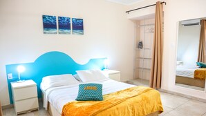 Een slaapkamer met een bed, nachtkastjes, een spiegel en een douchehoek.