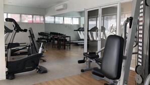 Un gimnasio con cintas de correr, máquinas de pesas y mancuernas.