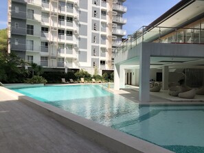 A modern hotel with a swimming pool, lounge chairs, and a multi-story building with balconies. - Casa Hermoso by Primitive Stay (Cebu City)