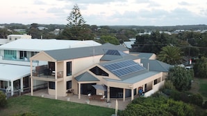 Una casa moderna de dos pisos con techo plano, paneles solares y un porche cubierto.