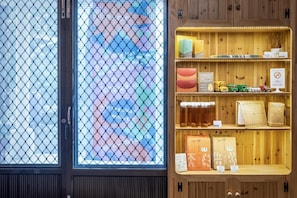 A room with a wooden shelf displaying books, bottles, and decorative items. - Mr Tanaka B&B (Fuli)