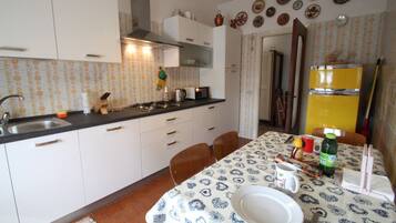 Een koelkast, een oven, een kookplaat, kookgerei, borden en bestek