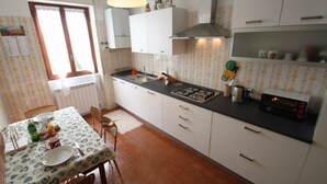 A kitchen with white cabinets, a black countertop, and a window with curtains. - Lake view Silvano Apartment (Baveno)