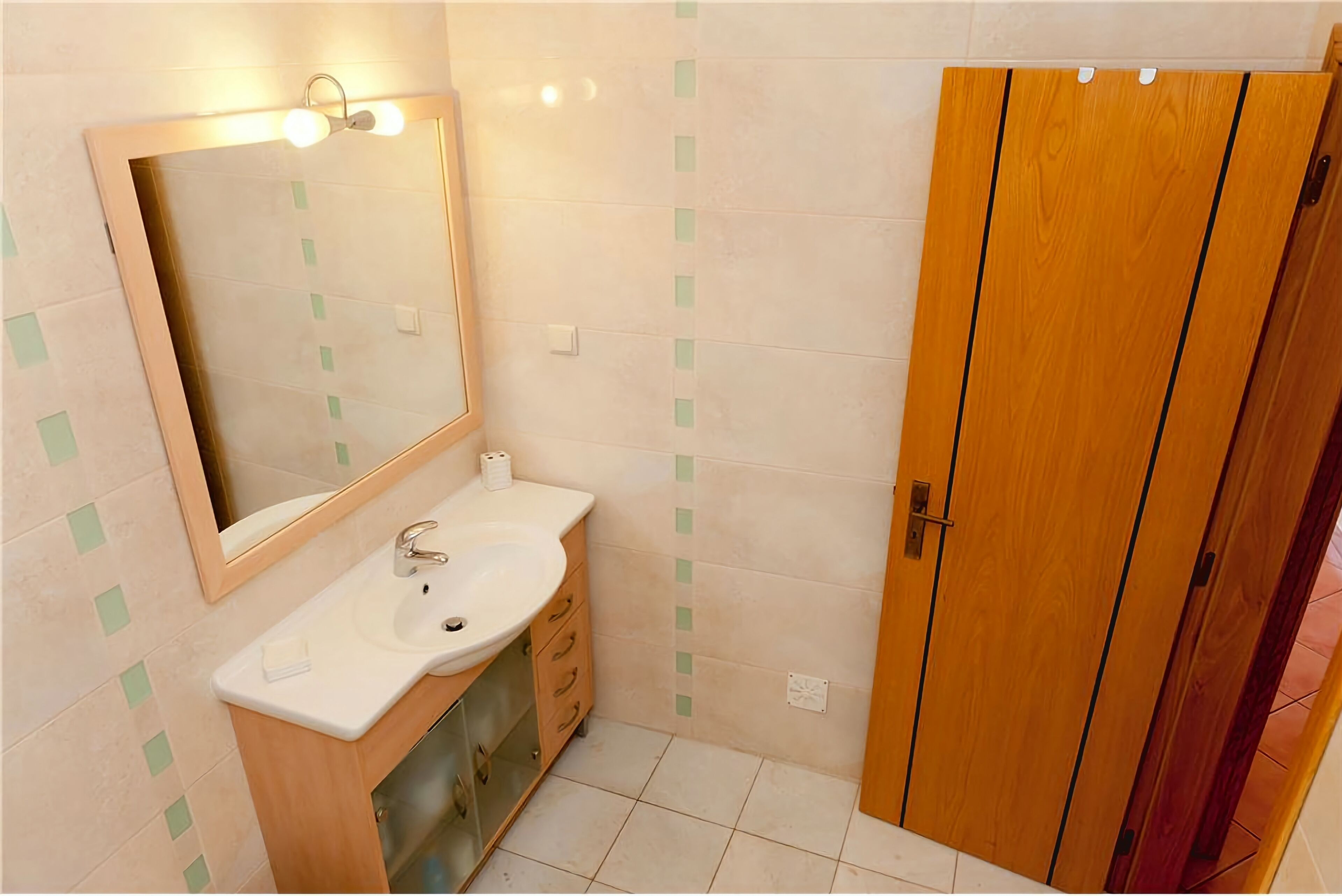 Une salle de bain avec un lavabo, un miroir et une porte en bois.