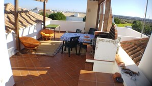 Un patio con una mesa y sillas, una silla de mimbre y vistas del entorno.