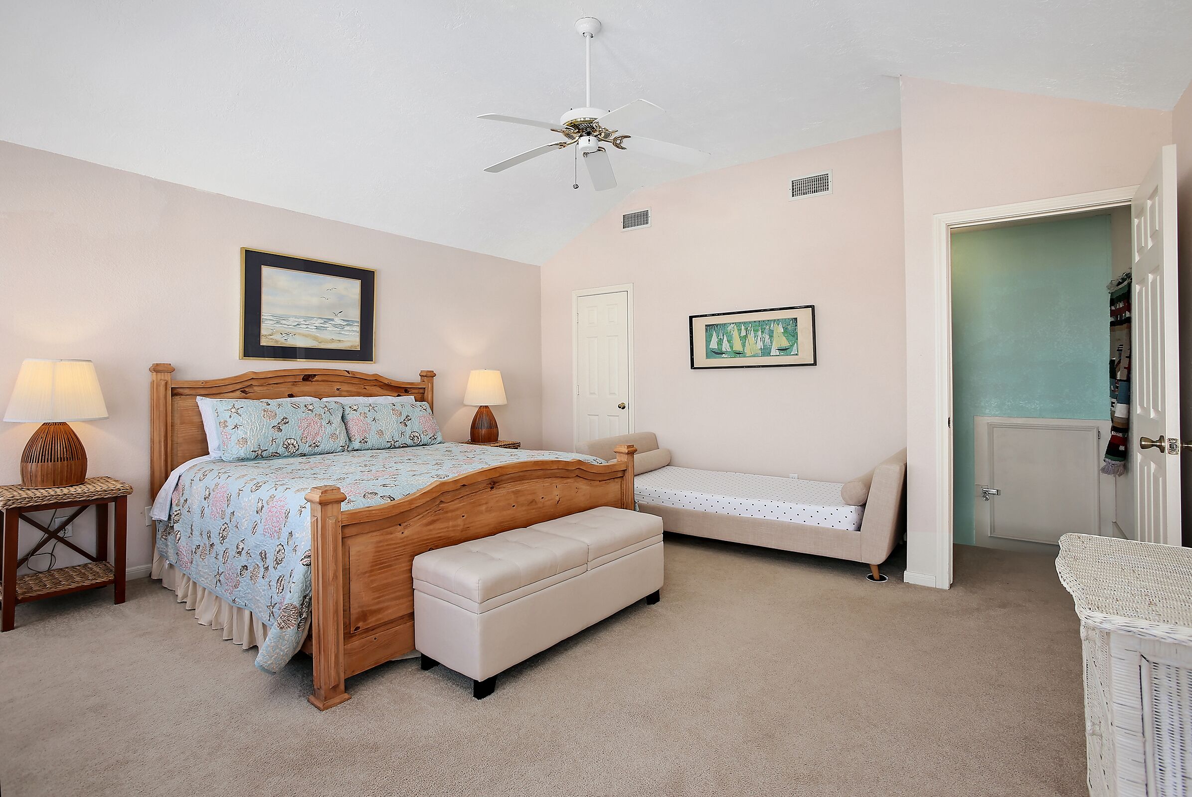 A bedroom with a wooden bed, a bench, a nightstand, two wall-mounted lamps, and a ceiling fan.