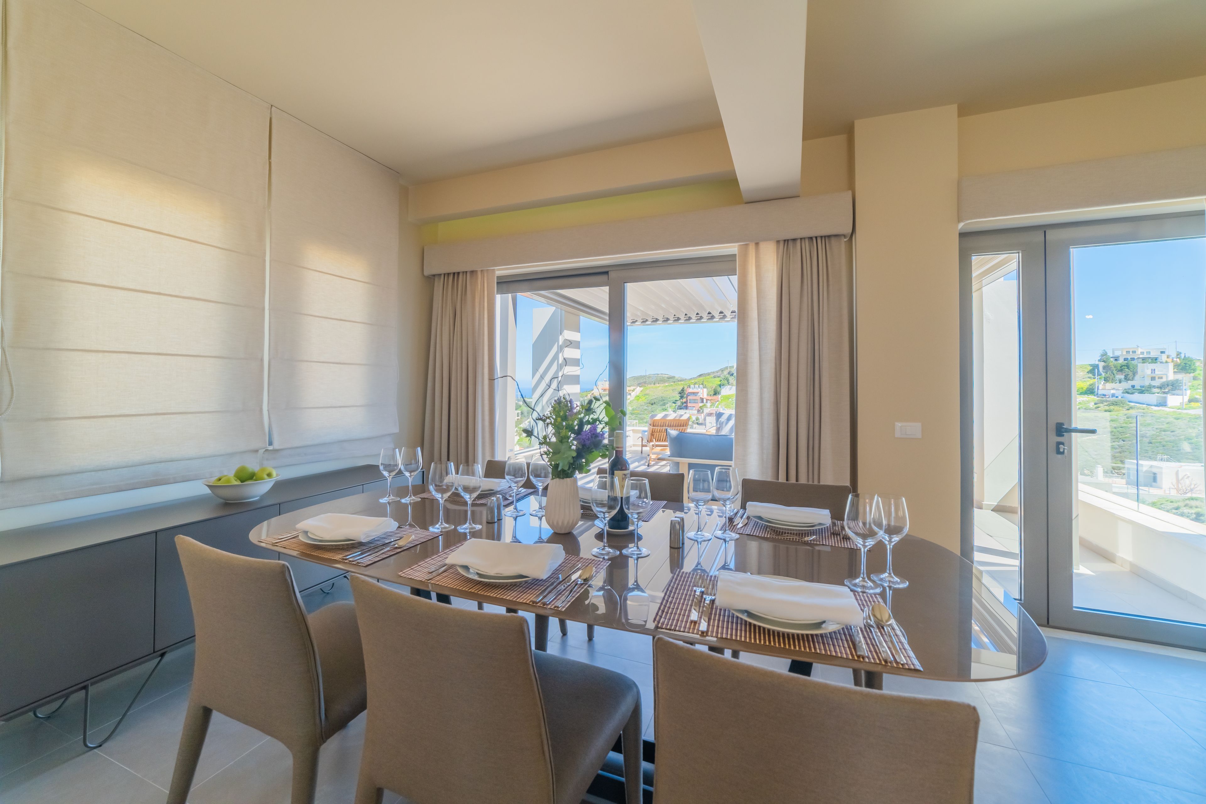 A dining area with a table set for six, large windows, and a view of the city.
