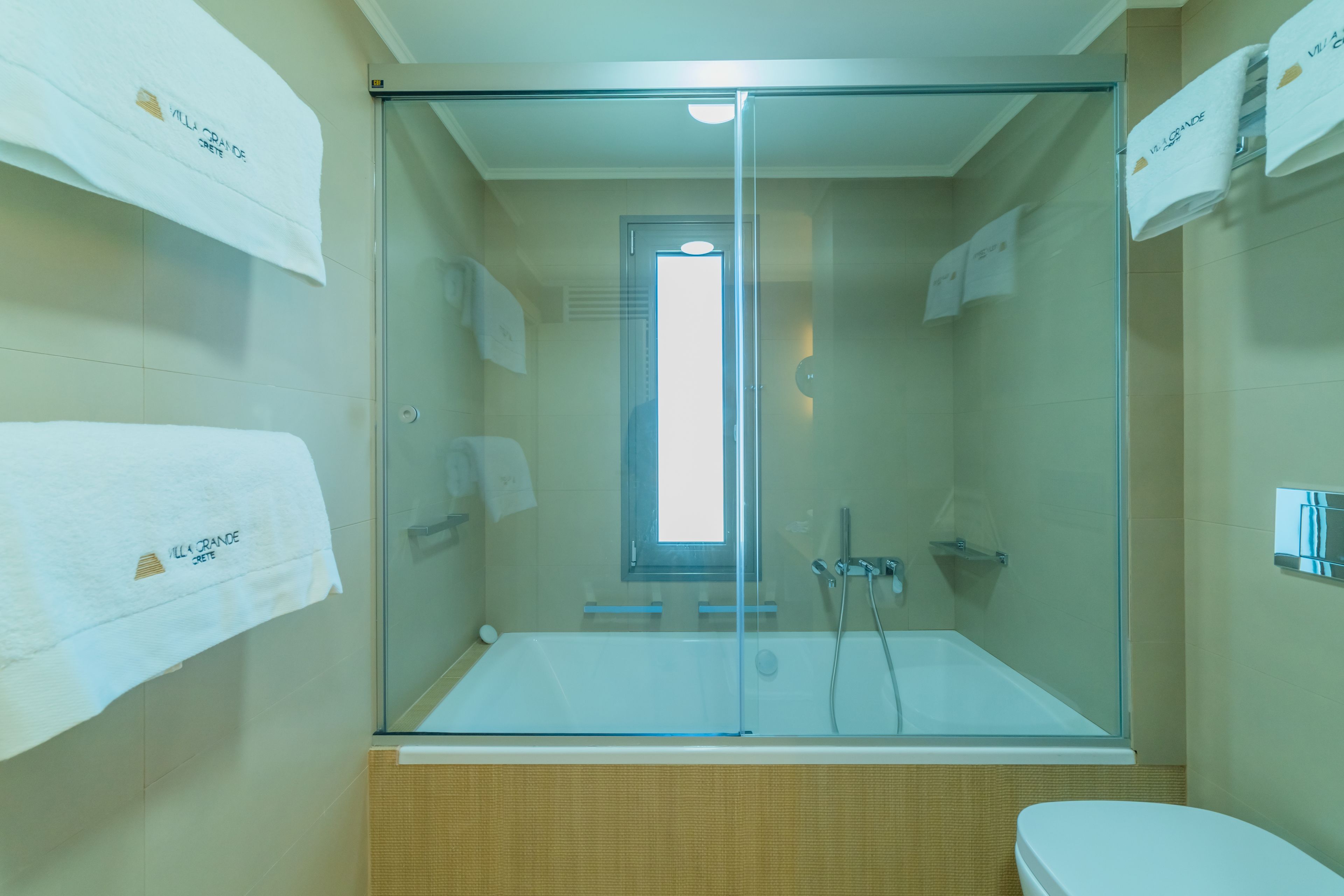 A modern bathroom with a glass-enclosed shower, a bathtub, and a toilet.