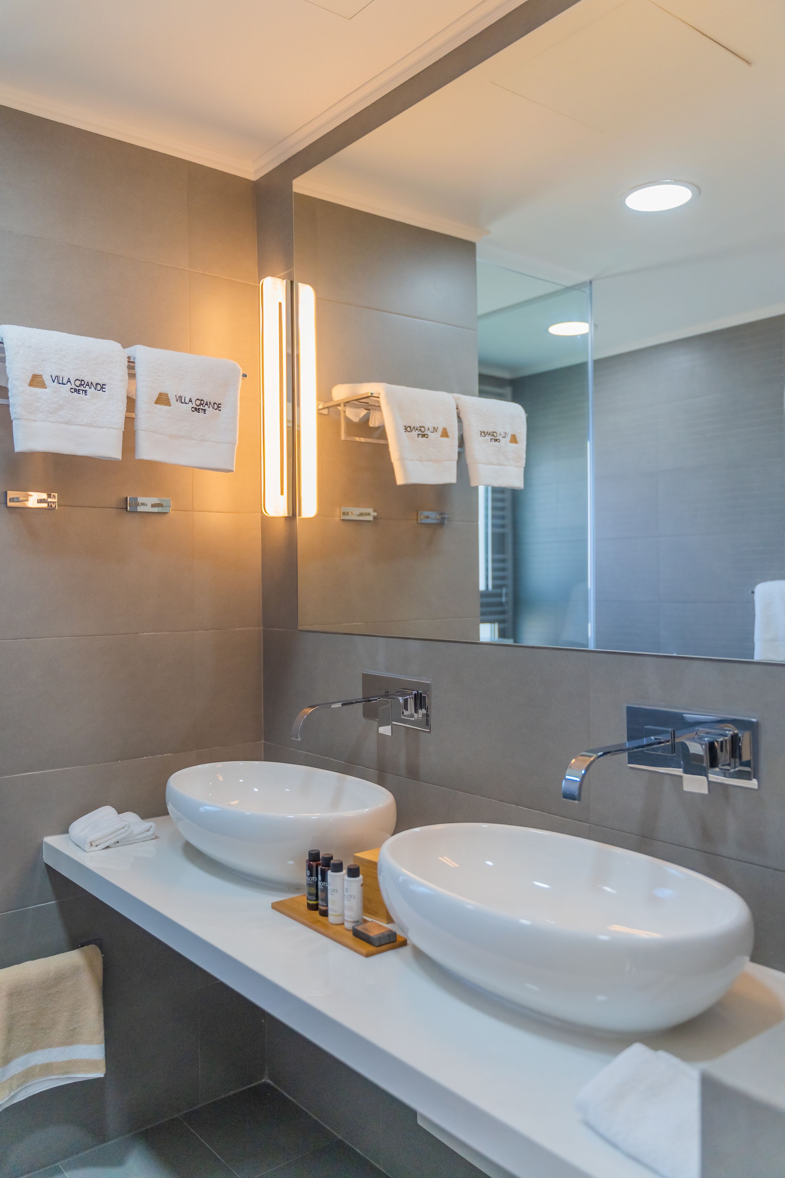 A modern bathroom with two large sinks, a mirror, and towels hanging on the wall.