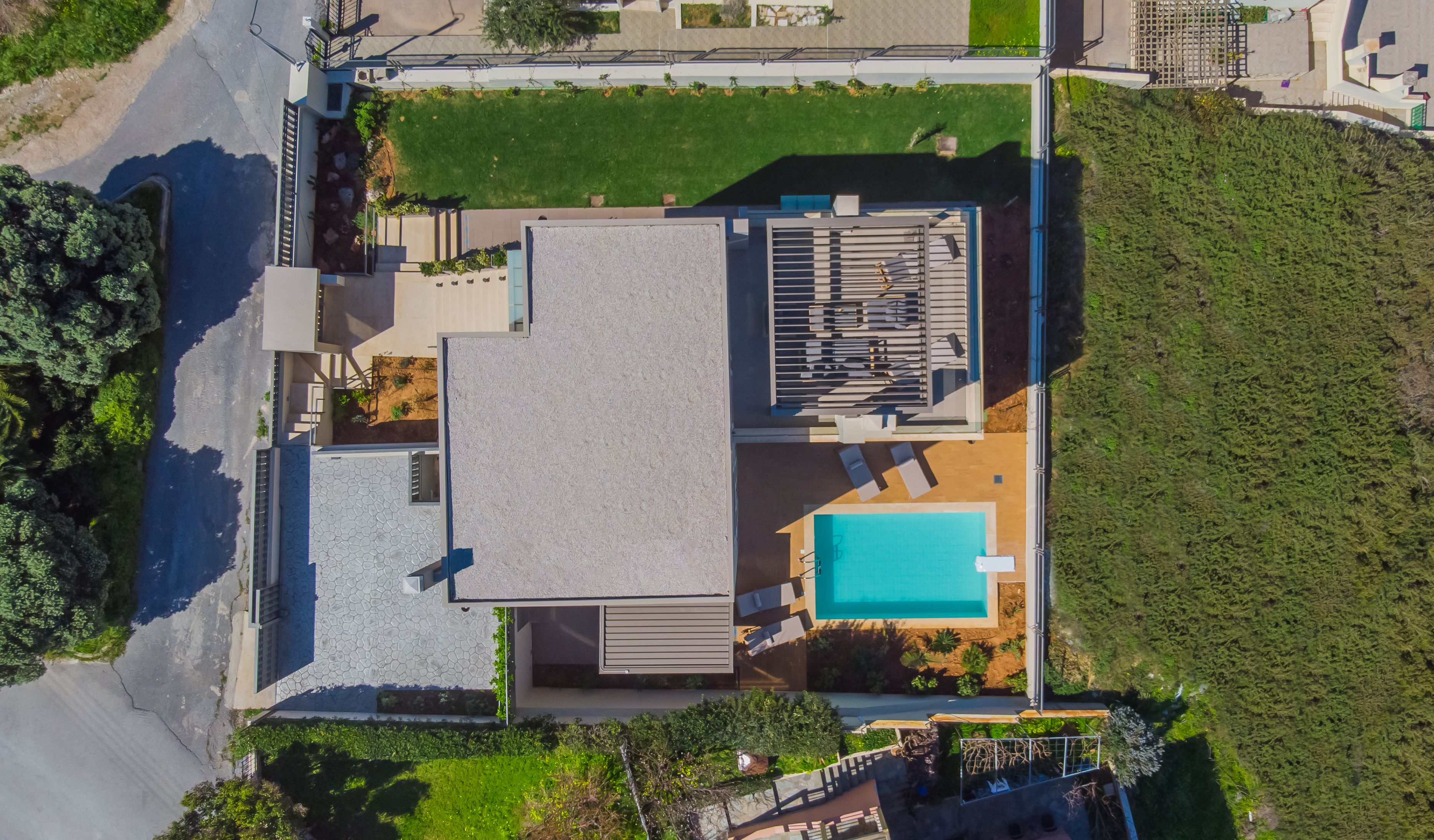 A modern house with a swimming pool, a covered patio, and a large garden.