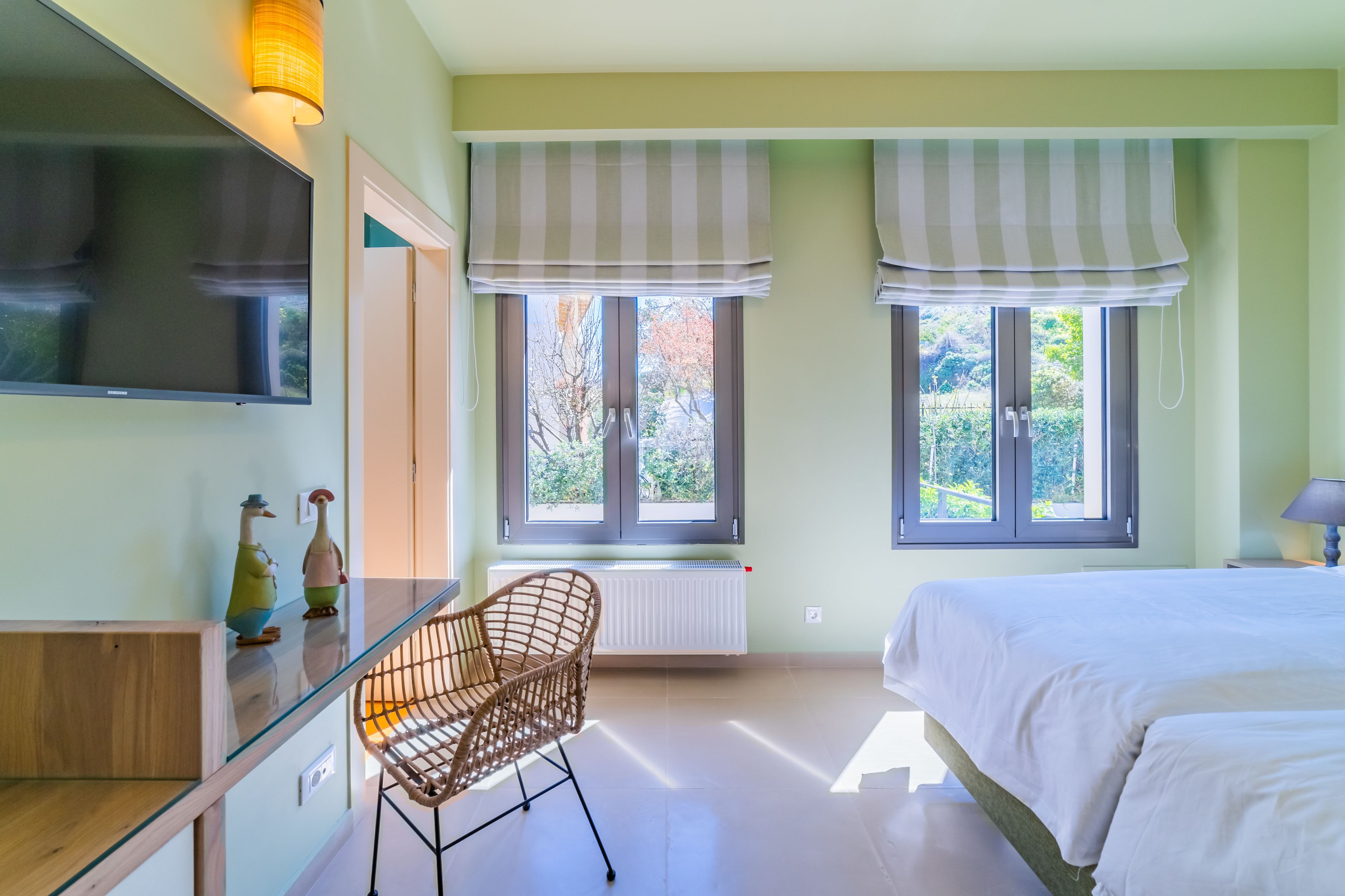 A bedroom with a bed, a chair, a radiator, and windows with curtains.