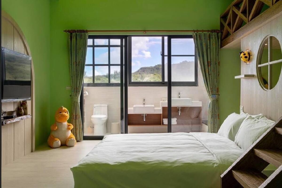 A bedroom with a large bed, a view of the bathroom, and a stuffed toy on the floor.
