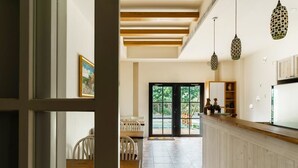 A modern kitchen with wooden beams, pendant lights, and a view through a glass door to an outdoor area. - Yiting B&B (Checheng)