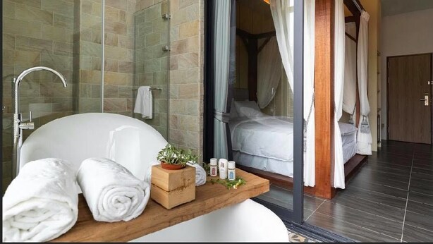 A modern bathroom with a bathtub, a wooden shelf with towels, and a glass shower enclosure. - Yiting B&B (Checheng)