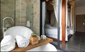 A modern bathroom with a bathtub, a wooden shelf with towels, and a glass shower enclosure. - Yiting B&B (Checheng)