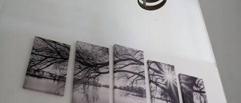 A ceiling light fixture and four black and white framed pictures on a white wall.