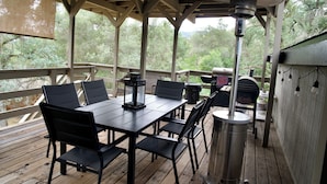 Una terraza techada al aire libre con mesa y sillas, una parrilla y un farol.