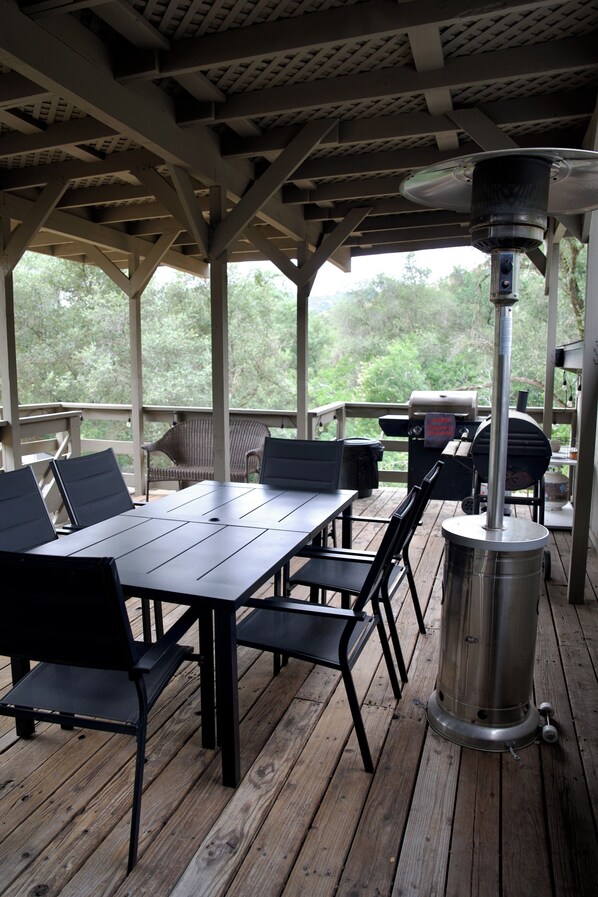 A covered outdoor area with a table and chairs, a grill, and a chimney.