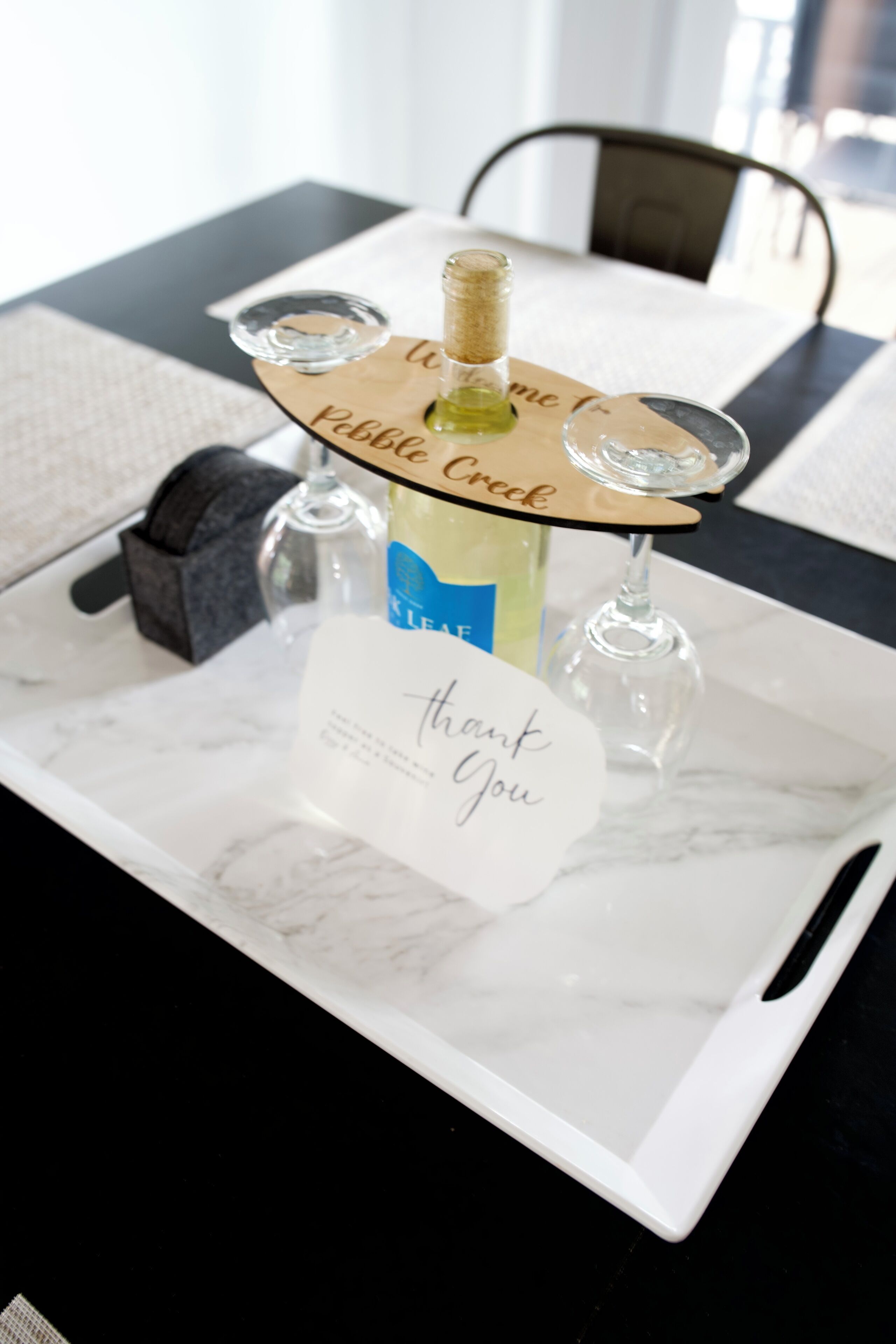 Une bouteille de champagne sur un plateau, accompagnée d’une carte de remerciement.
